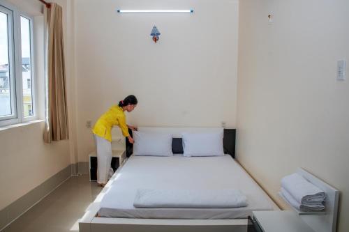 a woman standing next to a bed in a room at Sao Mai An Giang Hotel in Ấp Mỹ Thạnh