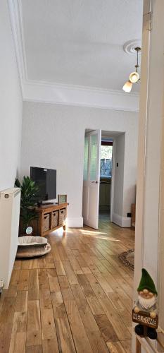 an empty living room with wooden floors and a flat screen tv at Home away from home in Aberdeen