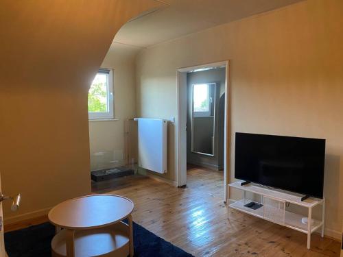 a living room with a flat screen tv and a table at Dachgeschosswohnung in Altbauvilla in Weilerbach