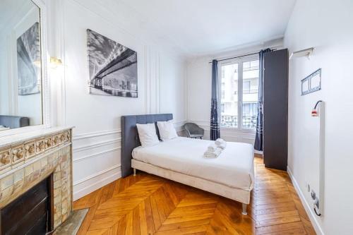 Cette chambre blanche dispose d'un lit et d'une cheminée. dans l'établissement Appartement Haussmannien proche Parc des Princes, à Paris