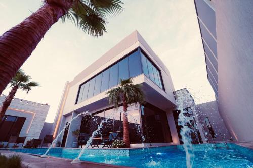 een gebouw met een fontein voor een gebouw met palmbomen bij Pool villa فيلا من ثلاث غرف نوم in El Mutainiyat
