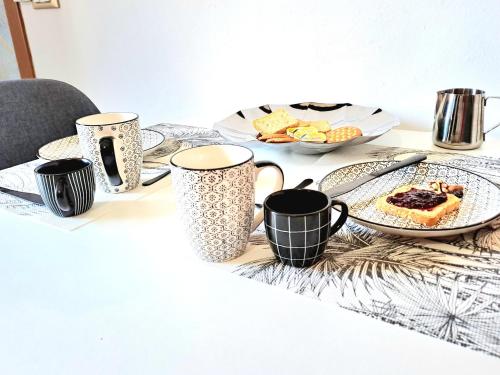 une table avec des tasses noires et blanches et une assiette de nourriture dans l'établissement A due passi da Milano - Rho Fiera - Malpensa - Como, à Saronno