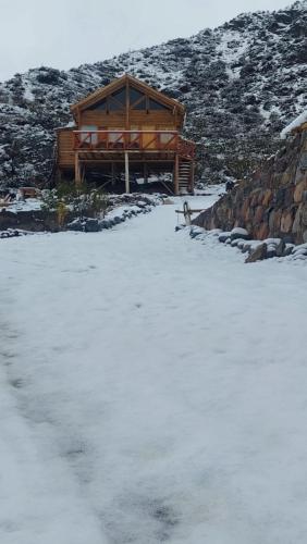 a building with snow on the ground in front at Cabaña Rincón del Sol in Potrerillos