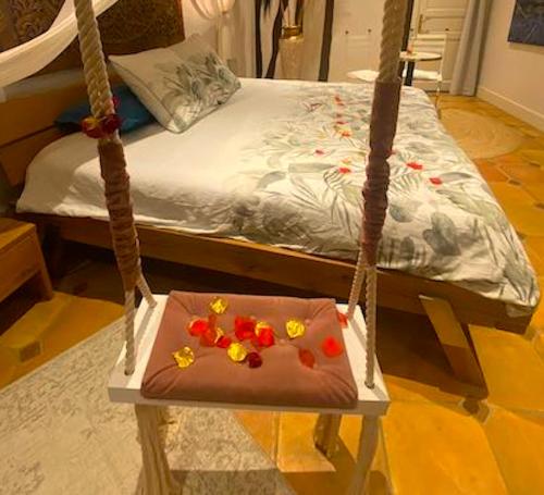 eine Schaukel mit Blumen darauf vor einem Bett in der Unterkunft 2 Suites romantiques avec spa privatif et 1 loft avec billard proche de Toulouse in Verfeil