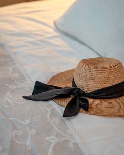 a straw hat with a black ribbon sitting on a bed at Mas des Comtes de Provence in Tarascon