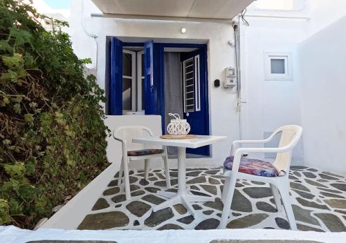 un tavolo bianco e sedie su una veranda con porta blu di Παραδοσιακή κατοικία στην αγορά a Paroikia