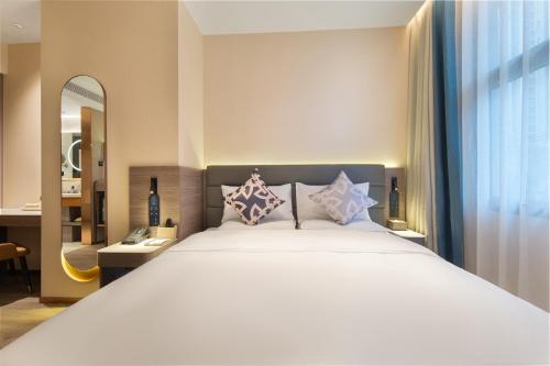 a bedroom with a large white bed and a mirror at 朗丽兹酒店深圳罗湖口岸店 in Shenzhen