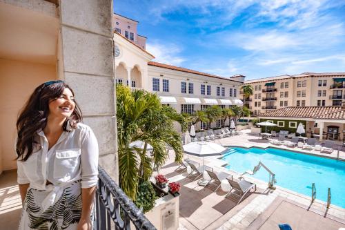 a woman standing on a balcony of a hotel with a pool at Hyatt Regency Coral Gables in Miami in Miami