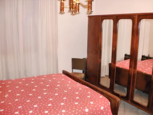 um quarto com uma cama com uma colcha vermelha com bolinhas em 2 bedrooms apartement at Nardo 600 m away from the beach with sea view and enclosed garden em Nardò