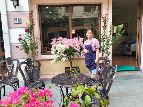フーコックにあるSunset Hotel Phu Quoc - welcome to a mixing world of friendsの花のテーブルの横に立つ女性