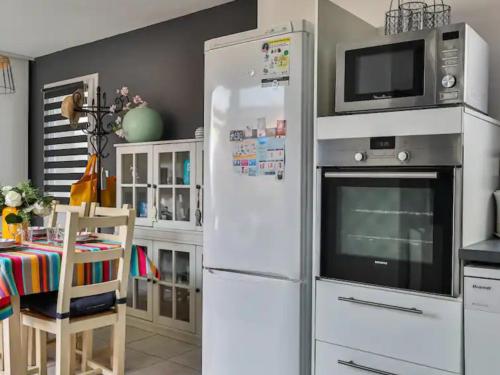 La cuisine est équipée d'un réfrigérateur blanc et d'un four micro-ondes. dans l'établissement Maison Les Agapanthes, à Les Sables-dʼOlonne