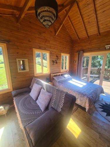 um quarto com uma cama, um sofá e janelas em Cabana Leão Baio em Urubici