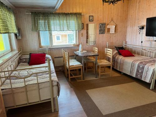 a bedroom with two beds and a table and chairs at Verlan Satumaa in Verla