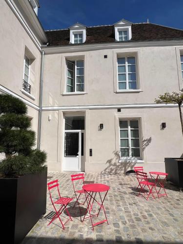 a group of red chairs and a table in front of a building at Le Laurencin Sens - Le cocon - Cœur de ville in Sens