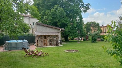 un patio trasero con 2 sillas y una tienda en el césped en Le camere dell'Albero Bianco con uso cucina, en Manzano