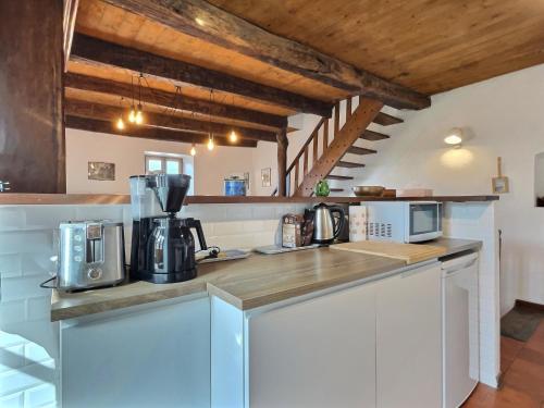 une cuisine avec des armoires blanches et un comptoir dans l'établissement Maison de la Fontaine, à Valleraugue