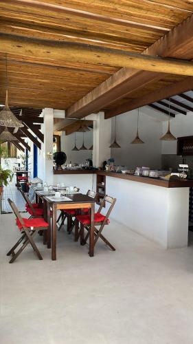 une salle à manger avec une table et des chaises rouges dans l'établissement Vila Mucugê Pousada e Hostel, à Arraial d'Ajuda