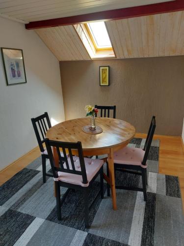 una mesa de madera con sillas y un jarrón de flores. en Haus Basilea en Wolfhalden 
