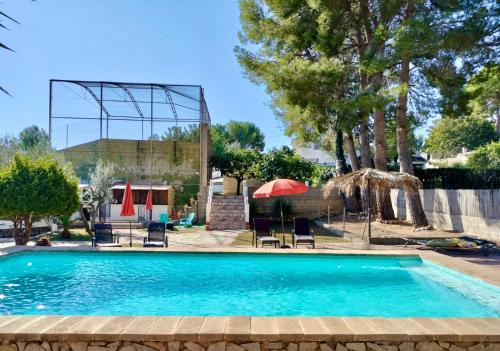 - une piscine avec des chaises et des parasols dans la cour dans l'établissement Casa Mas Montanas vakantiehuis met zwembad Max 10 pers Vlakbij Valencia, à Godelleta