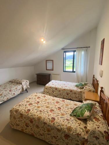 1 dormitorio con 3 camas y ventana en A CASA DE SISAN, en Ribadumia