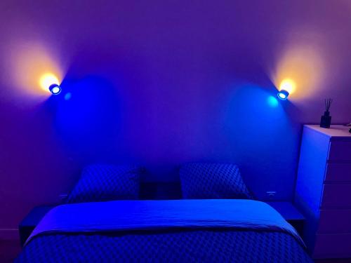 a bedroom with a bed and two lights on the wall at Chambre Confort - Douche Privative - Jardin - Parking Gratuit in Argenteuil