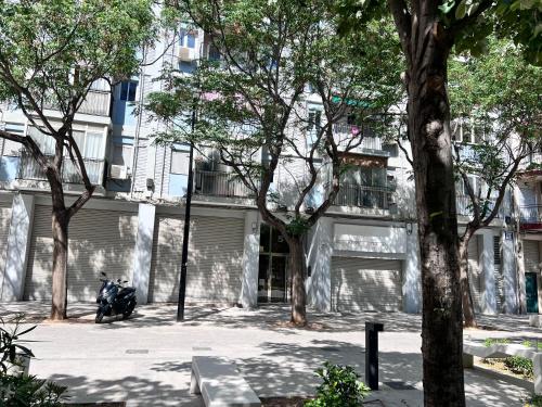 een motorfiets geparkeerd voor een gebouw met bomen bij Plaza Sainetero Arniches in Valencia
