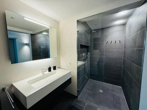 a bathroom with a sink and a shower with a mirror at Aqua Aura - Deluxe Spa Getaway with Sauna & Pool in Stegen