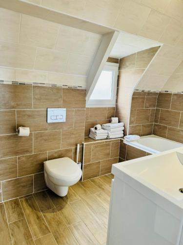 a bathroom with a toilet and a sink and a tub at Le Clos Normand in Saint-Aubin-sur-Mer