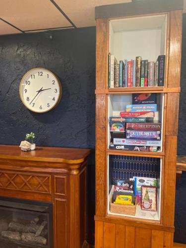a clock on a wall next to a book shelf with books at Skyline Village Inn in Spruce Pine
