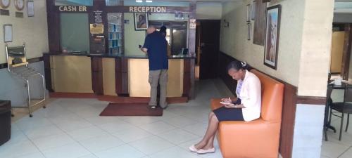 a woman sitting in an orange chair in a lobby at Kipepeo Sky View in Nairobi