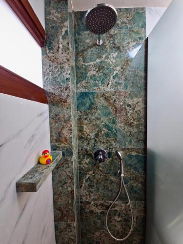 y baño con ducha y pared de piedra. en Theros Aegean Villa en Iraklitsa