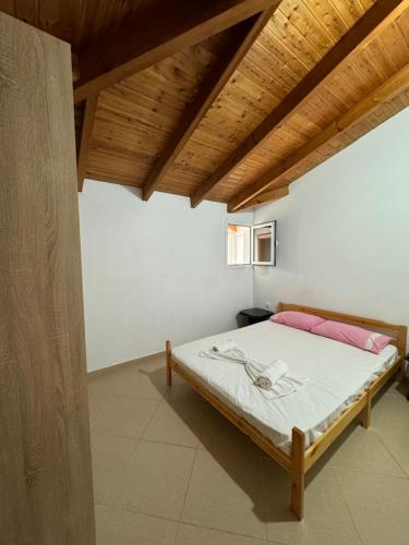 Cama en habitación con techo de madera en L.T. Apartment 5th street, en Sarandë