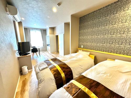 um quarto de hotel com duas camas e uma televisão em Resort Stay Spa Tsurumi em Beppu
