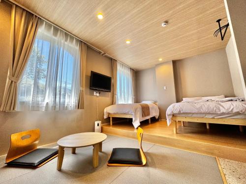 a bedroom with two beds and a table and a window at Beppu onsen Resort Stay Spa Tsurumi in Beppu