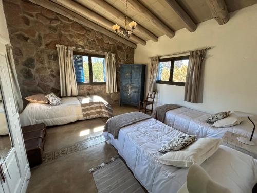 a bedroom with three beds and a stone wall at Casita de ensueño Andes Crucecita in Las Compuertas