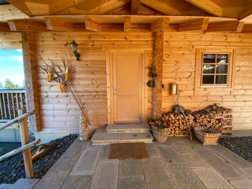 a wooden cabin with a door and a pile of logs at Almhütten Skorianz- Die Grüne Hirschhütte in Klippitztorl