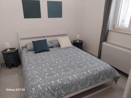 una camera da letto con un letto con un piumone e cuscini grigi di Casa Flavia a Torre Chianca