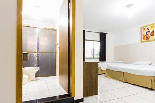 a hotel room with two beds and a bathroom at Hotel Holiday Foz in Foz do Iguaçu