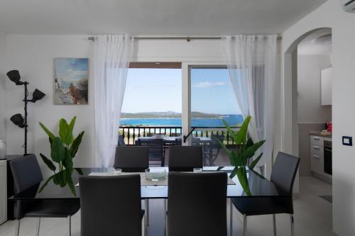 Un comedor con mesa y vista al mar. en Harenae Beach Gataway by Wonderful Italy, en Porto Rotondo