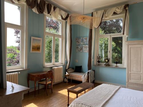 1 dormitorio con 1 cama, escritorio y ventanas en B&B Le Manoir de la Douve, en Heuvelland