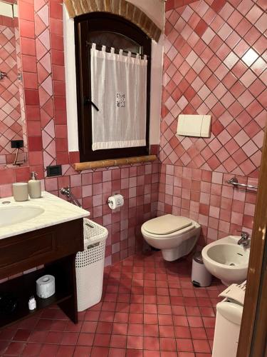 een roze betegelde badkamer met een toilet en een wastafel bij Bilocale Dafne Abbadesse Guest House in Milaan