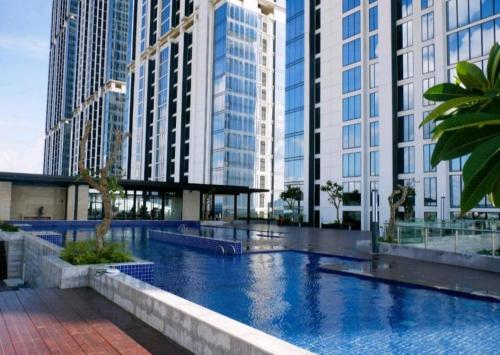 a large swimming pool in a city with tall buildings at Serene Studio Pollux Batam Center - High Floor Sea View in Batam Center