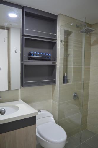 y baño con aseo y ducha acristalada. en Apartamento Treboles en Cali