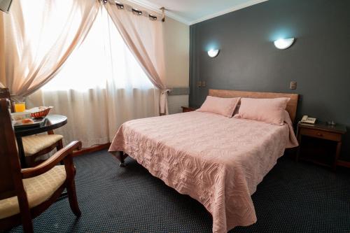 Hotel Vitali في كونثبثيون: غرفة نوم بسرير وبطانية وردية ونافذة