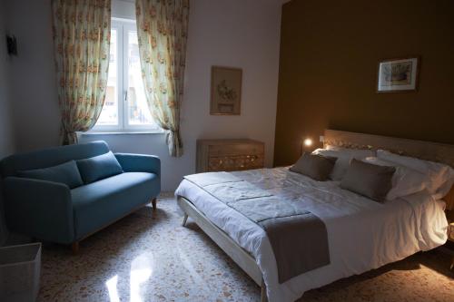 a bedroom with a bed and a blue chair at Diana Home - Rooms and Suite in Caserta