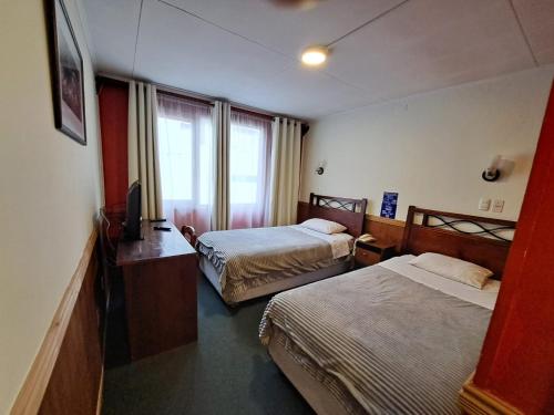 ein Hotelzimmer mit 2 Betten und einem TV in der Unterkunft Hotel Condor de Plata in Punta Arenas