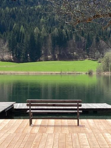 a wooden bench sitting on a dock next to a lake at Apartments Kolbitsch mit Seeblick in Weissensee