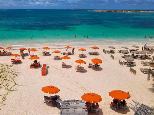 an overhead view of a beach with orange umbrellas and the ocean at Villa Marguerite private pool and hot tub in Orient Bay in Orient Bay