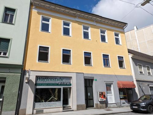 un edificio amarillo en una calle con una tienda en City-Apartments Graz, en Graz