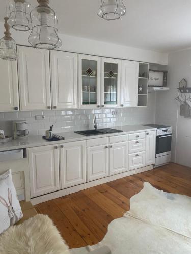 uma cozinha branca com armários brancos e piso em madeira em Lomnice nad Popelkou em Lomnice nad Popelkou